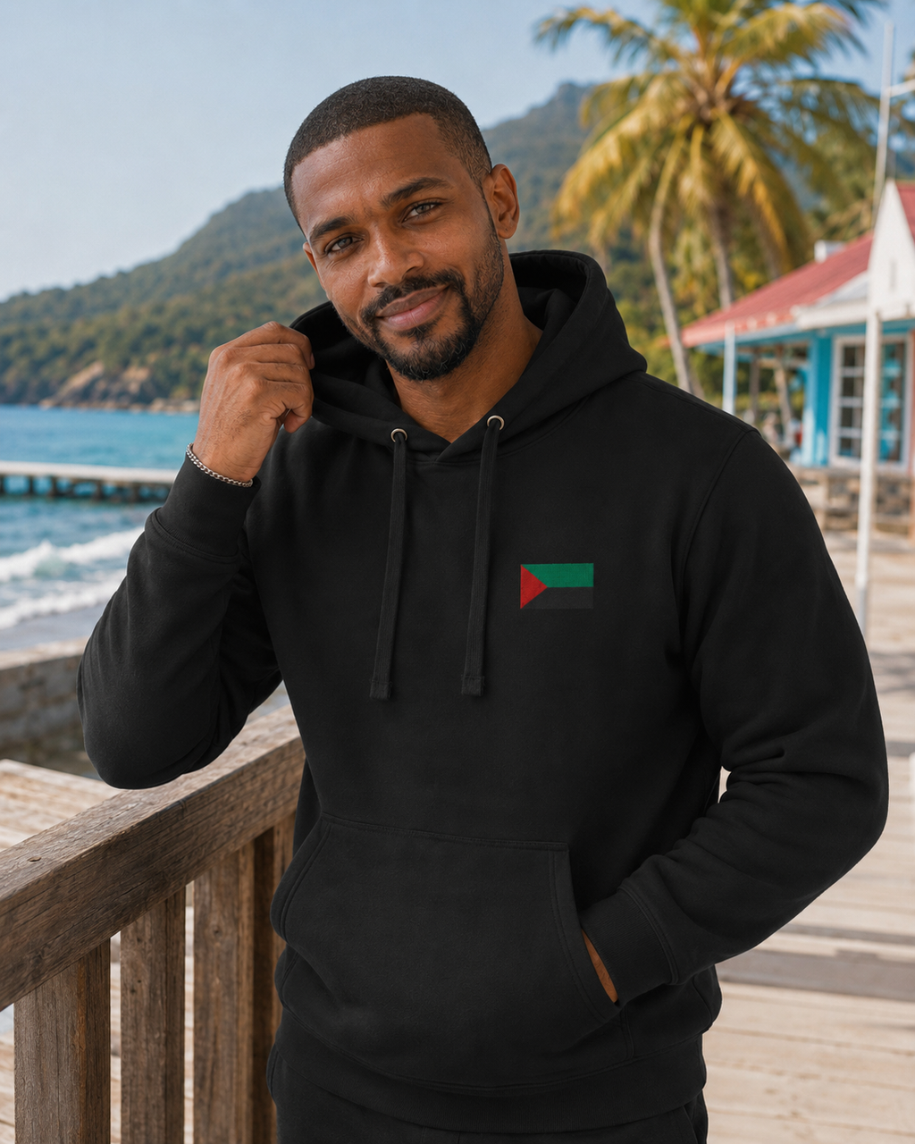 Hoodie RVN Martinique noir unisexe porté par un homme sans casquette en bord de mer, vue de face.